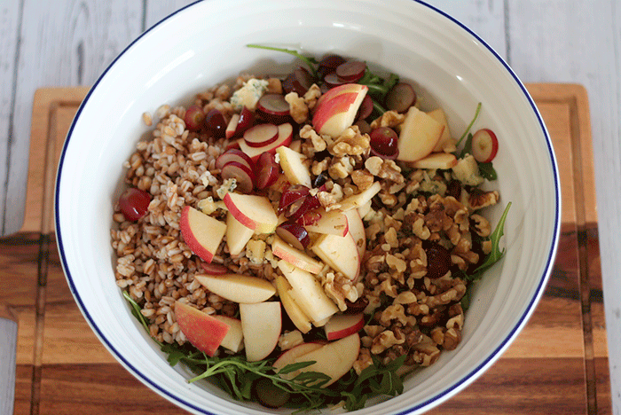 pearled spelt, leaves, apples, grapes, blue cheese and walnuts combined in a large salad bowl