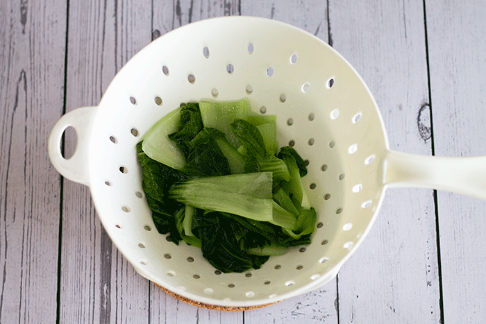 cooked pak choi in colander