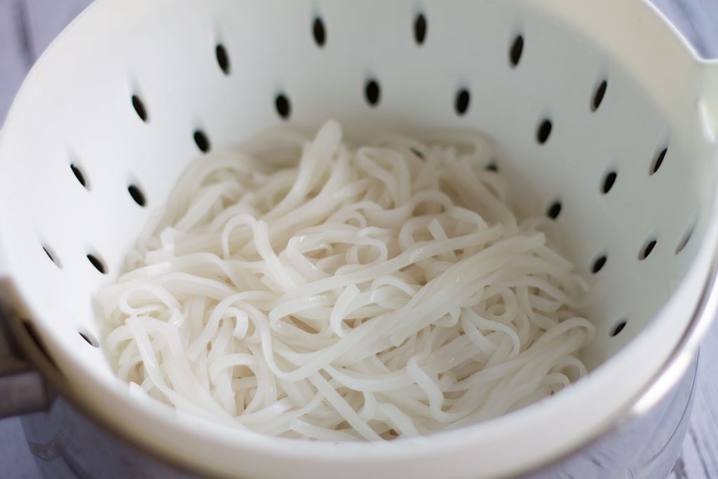 cooked rice noodles in a colander