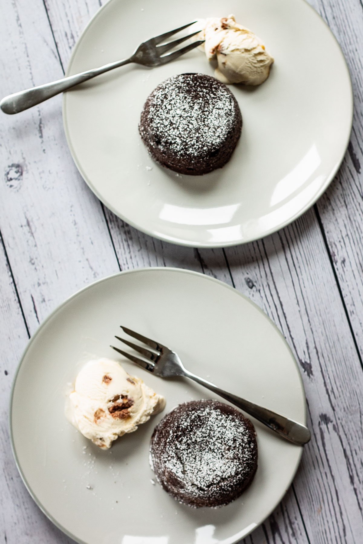 Two plates with fondant cakes served with ice cream. 