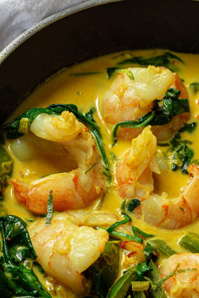Close up of cooked prawn curry with coconut milk in a frying pan