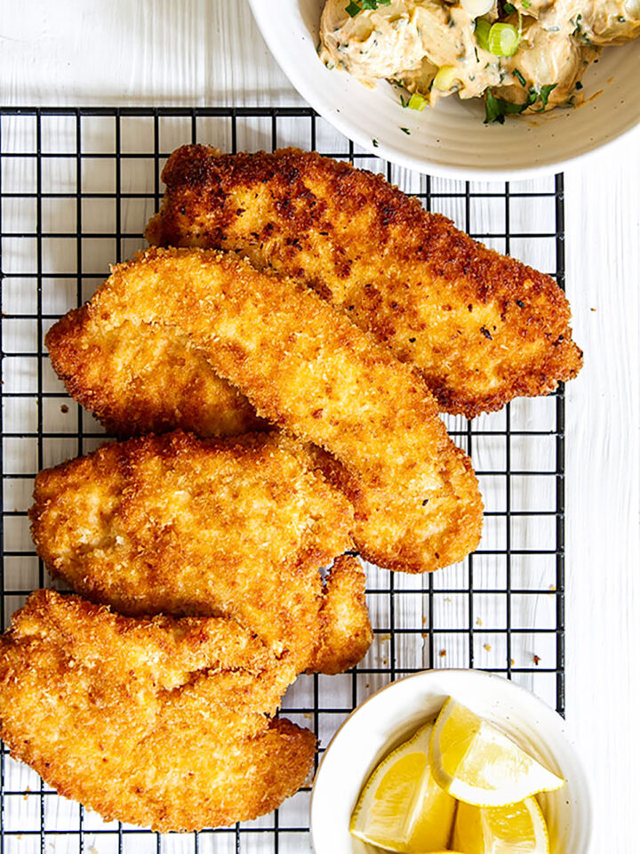 Panko chicken on wire rack with lemon wedges.