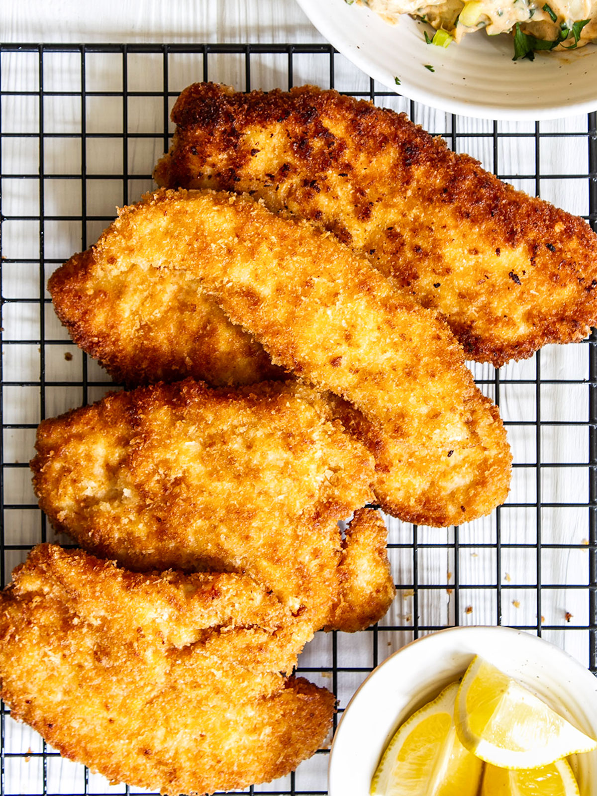 Panko chicken on wire rack with lemon wedges.