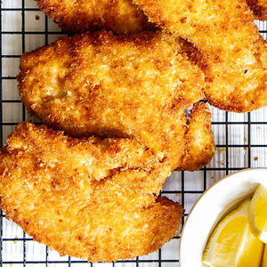 Panko chicken on wire rack with lemon wedges.