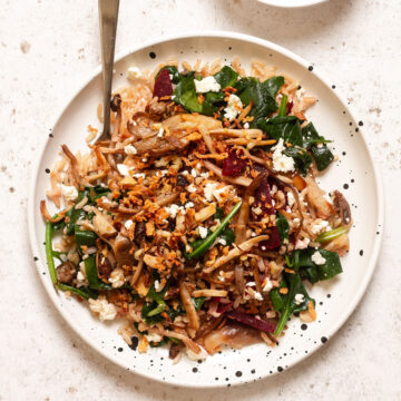 warm mushroom salad served on a plate with crunchy onions and dressing on the side