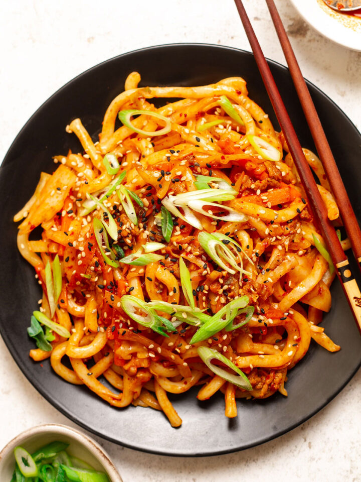 Spicy Korean noodles on a black plate.
