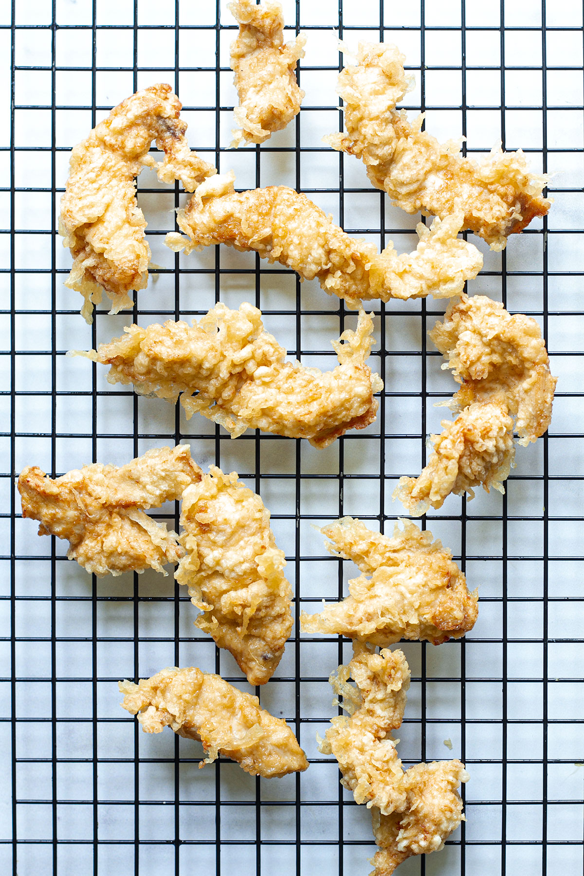 Fried battered chicken tempura pieces on a wire rack.