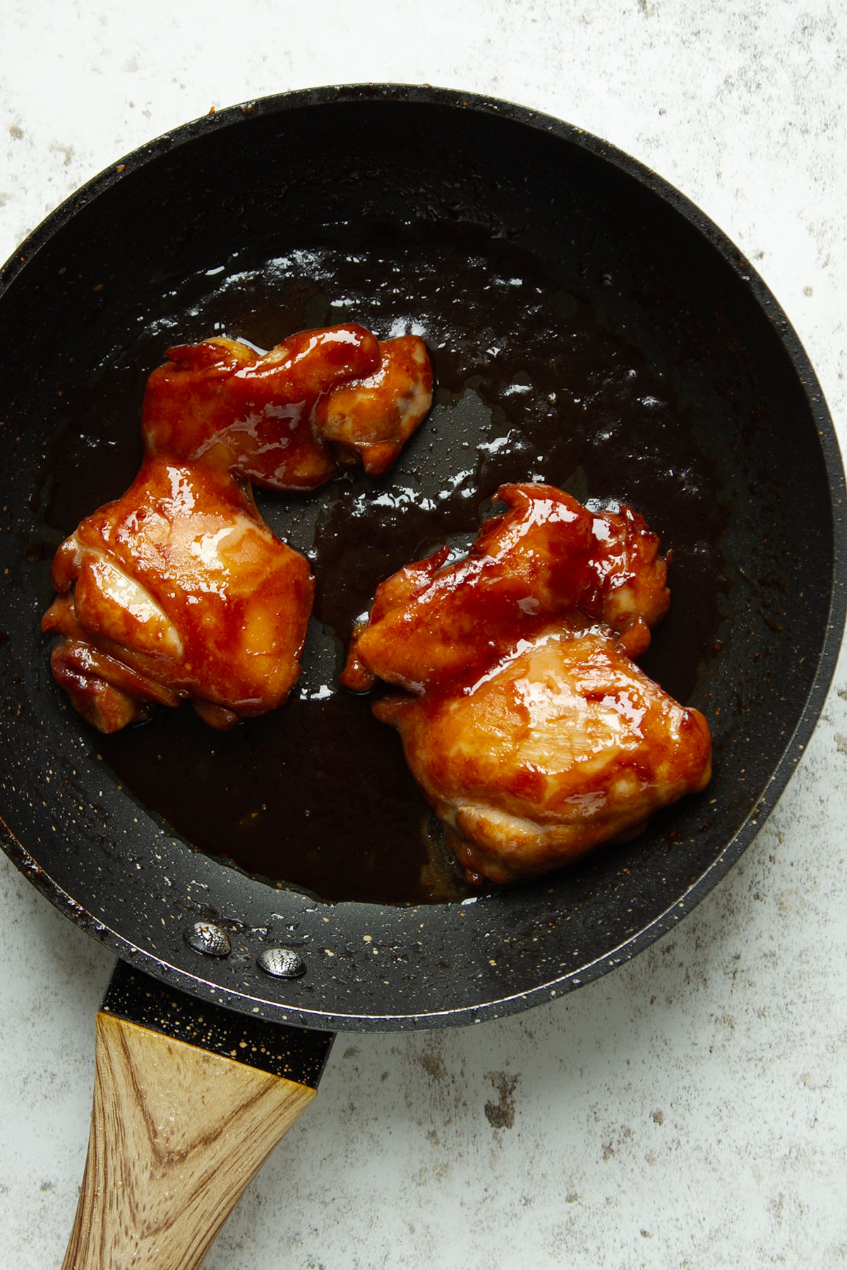 Simmering the chicken in the marinade in a pan on a white background.