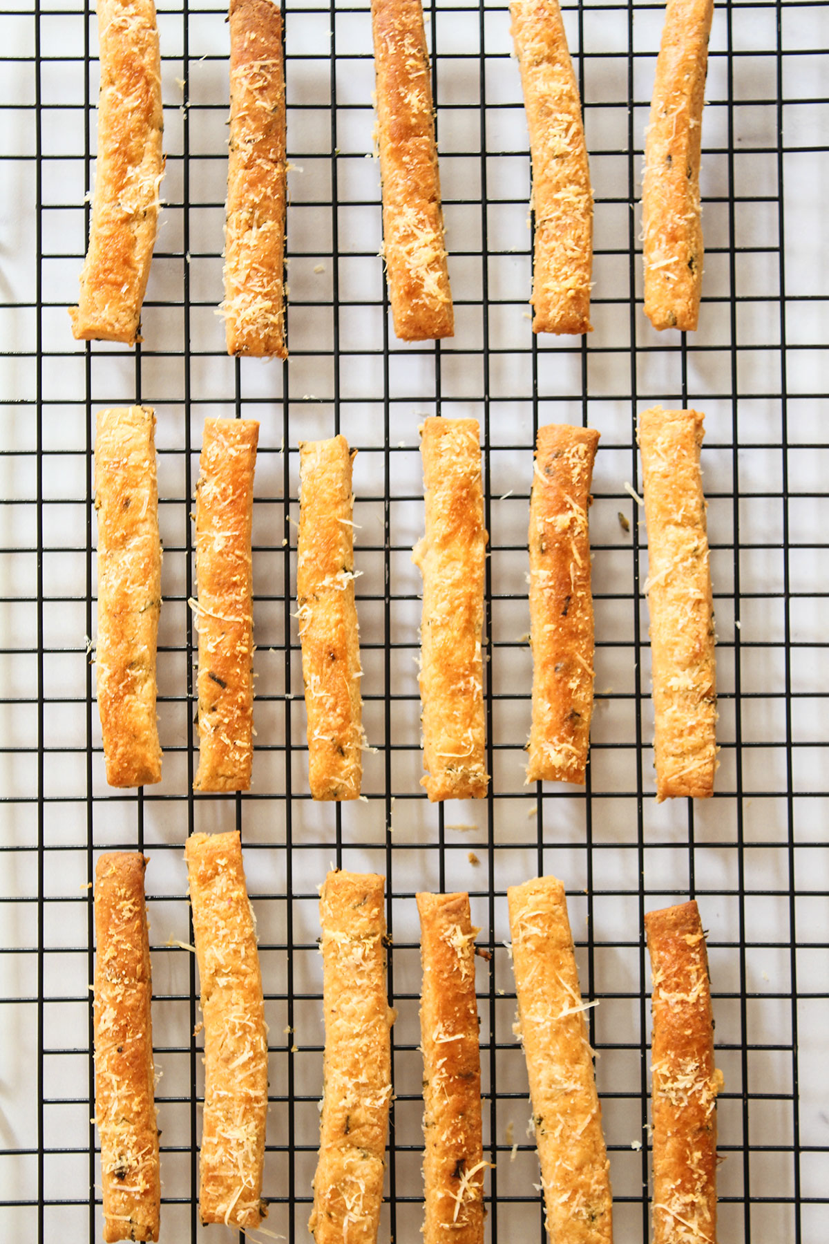 The baked cheese straws cooling on a wire rack.