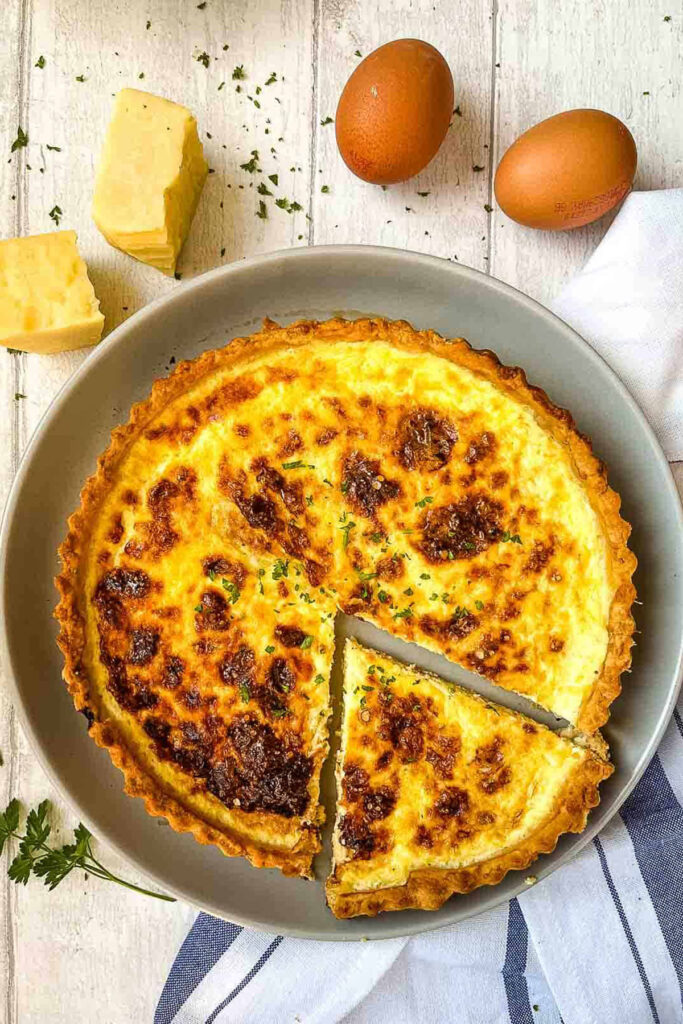 A cheese flan in a grey dish garnished with parsley.