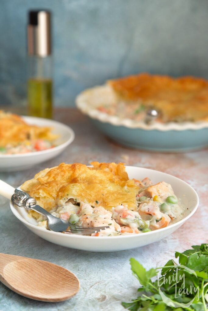 2 bowls of salmon pot pie with the whole pie in the background.