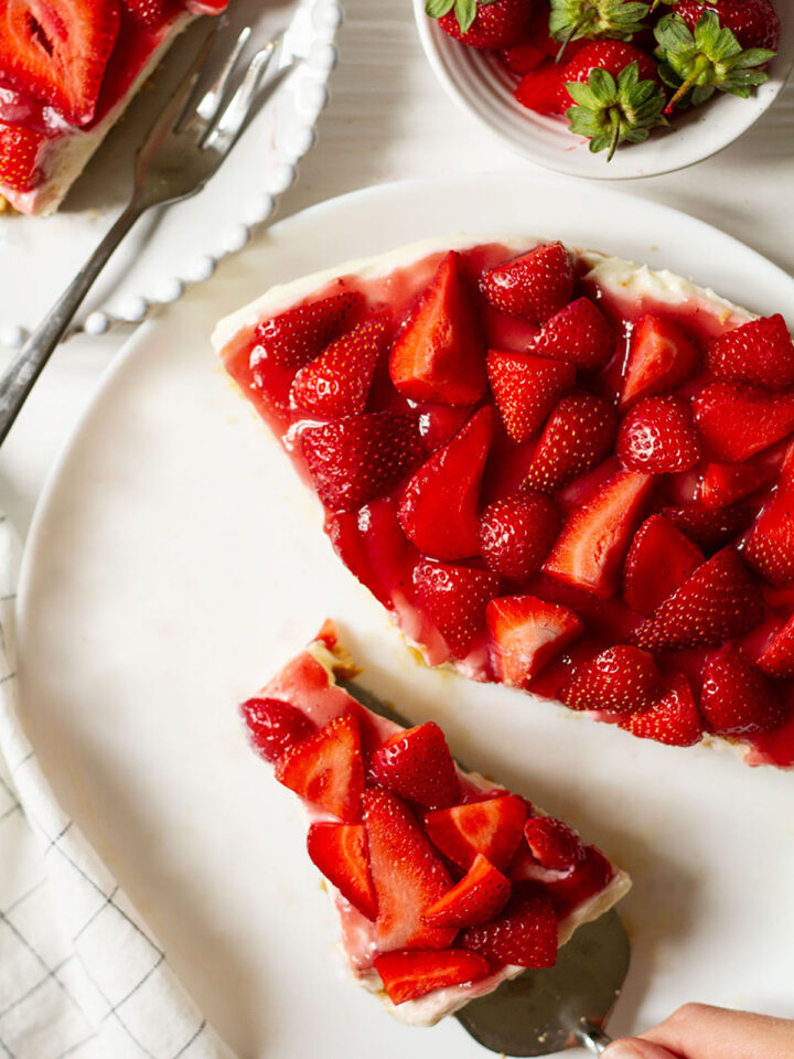 No Bake Strawberry Cheesecake served on a white plate with a side of whole strawberries.