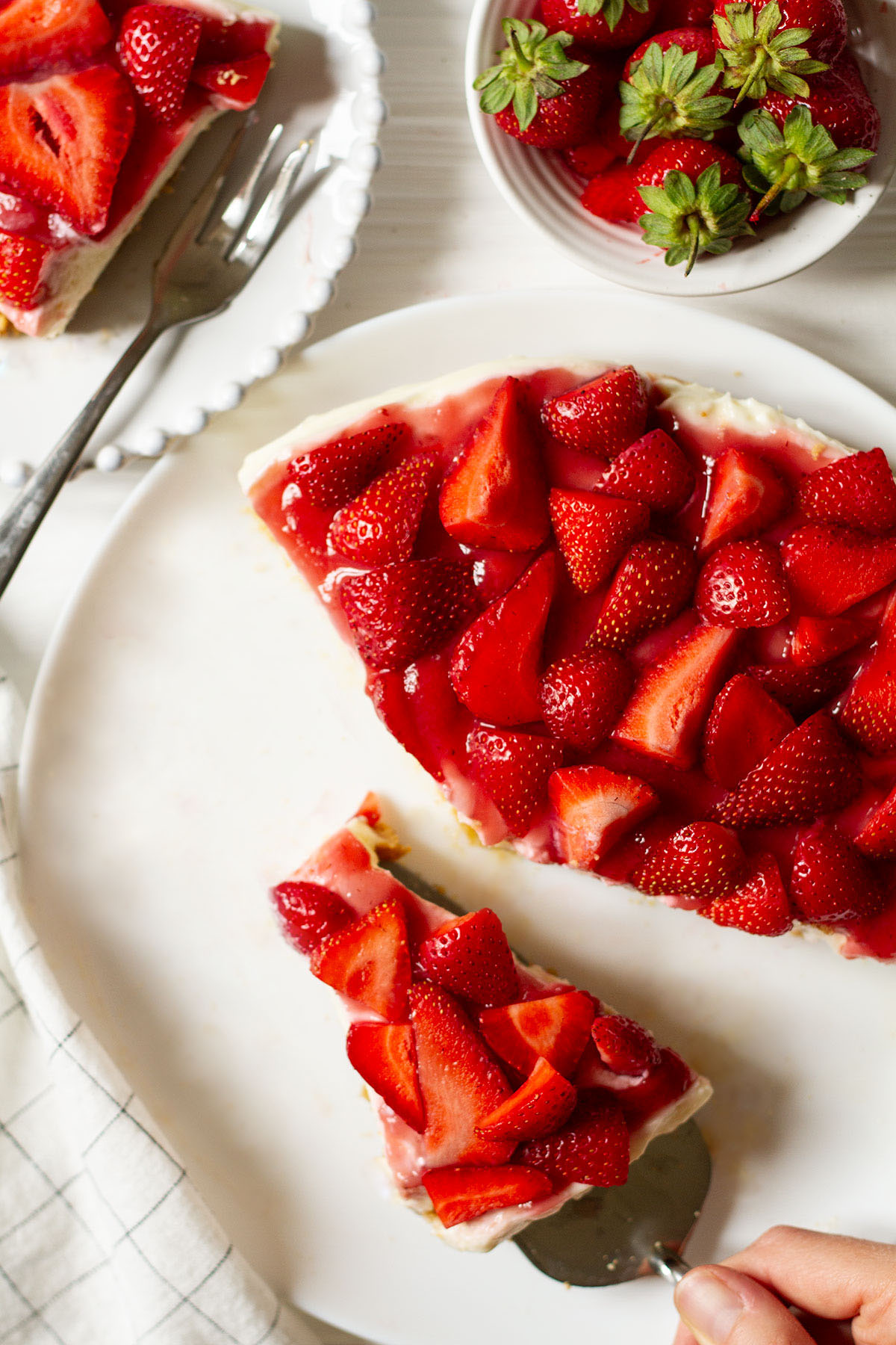 No Bake Strawberry Cheesecake served on a white plate with a side of whole strawberries.