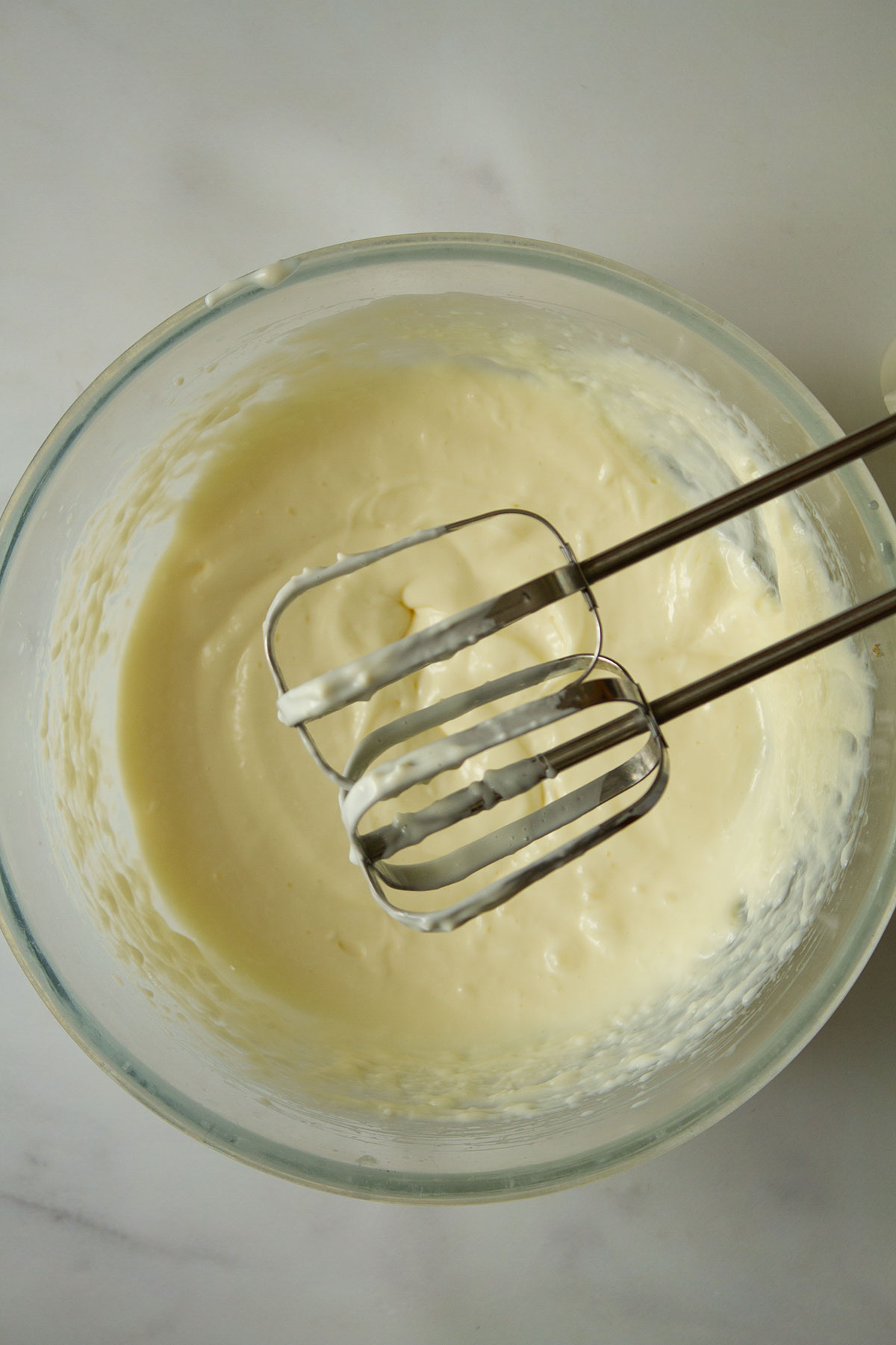 Combining the Philadelphia and condensed milk in a mixing bowl using an electric whisk.
