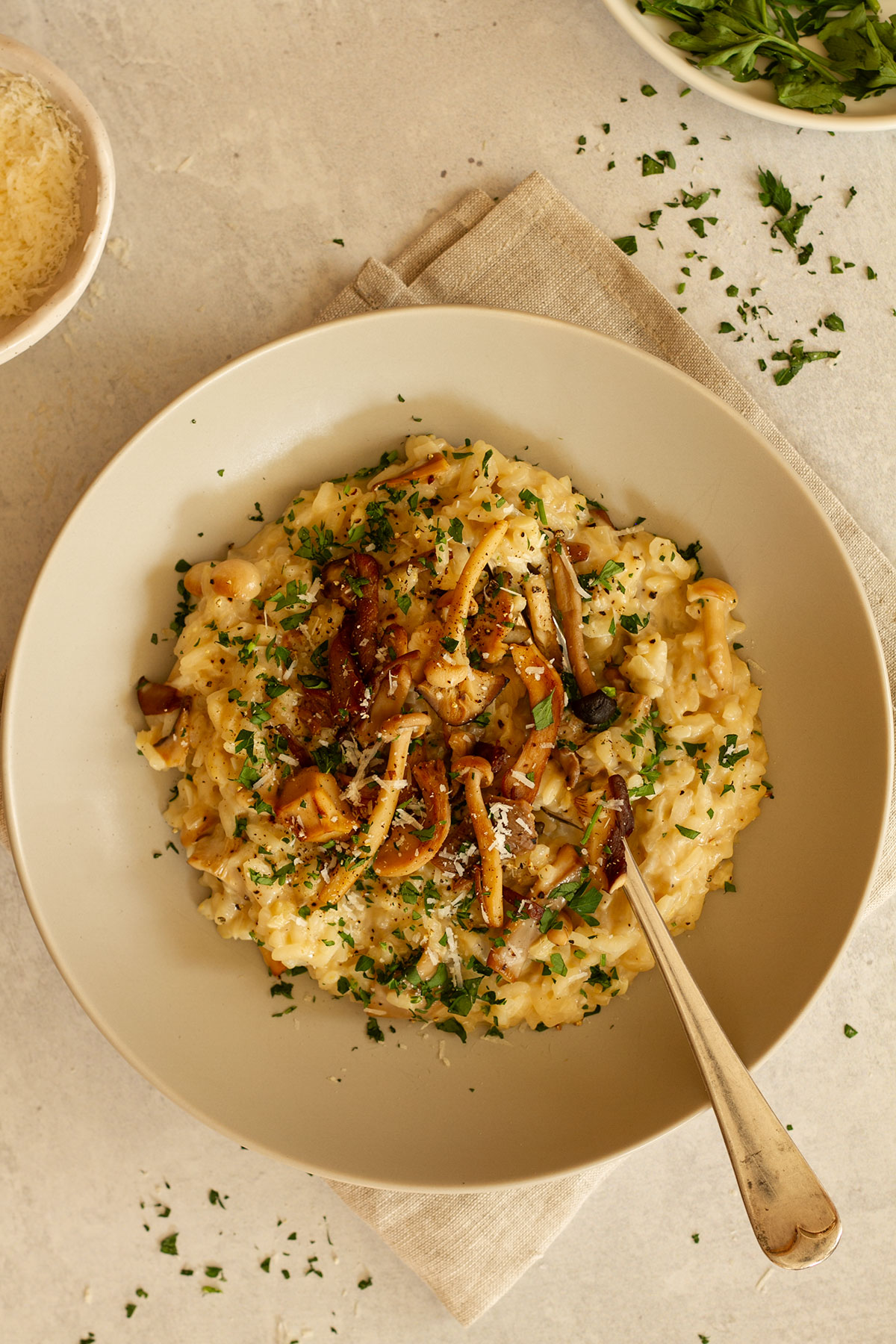 A serving of Mushroom Risotto on a cream coloured plate with parsley and Parmesan.