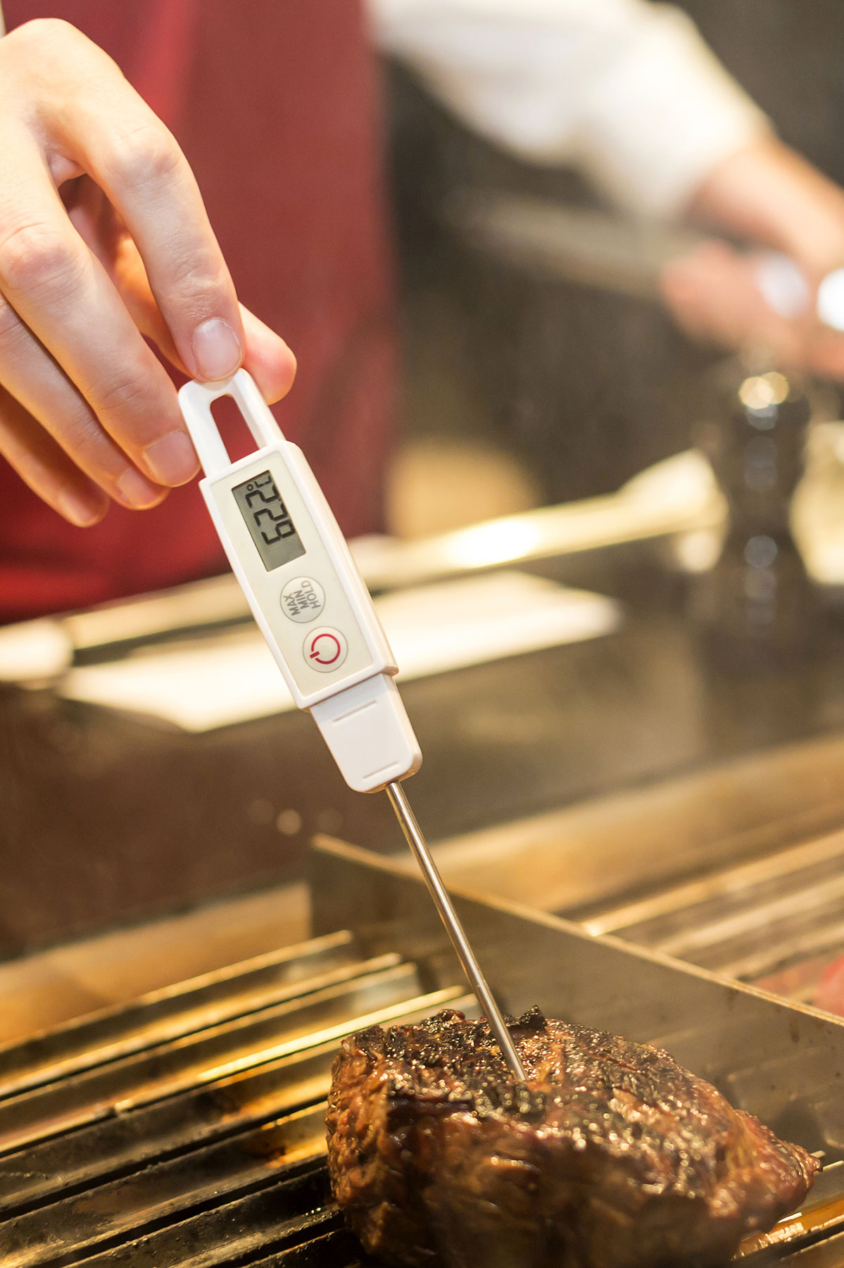 A piece of cooked steak with an instant read thermometer inserted.