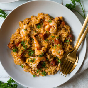 Chorizo and Prawn Risotto served on a white plate on a white tiled background.