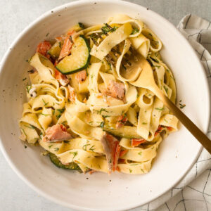 A serving of salmon and dill pasta in a white bowl.