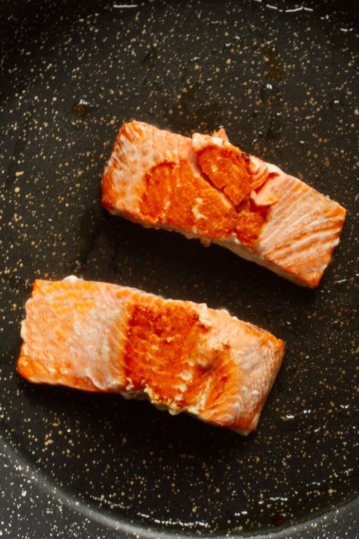 Pan-frying the salmon fillets for 2-3 minutes on each side until they are cooked through.