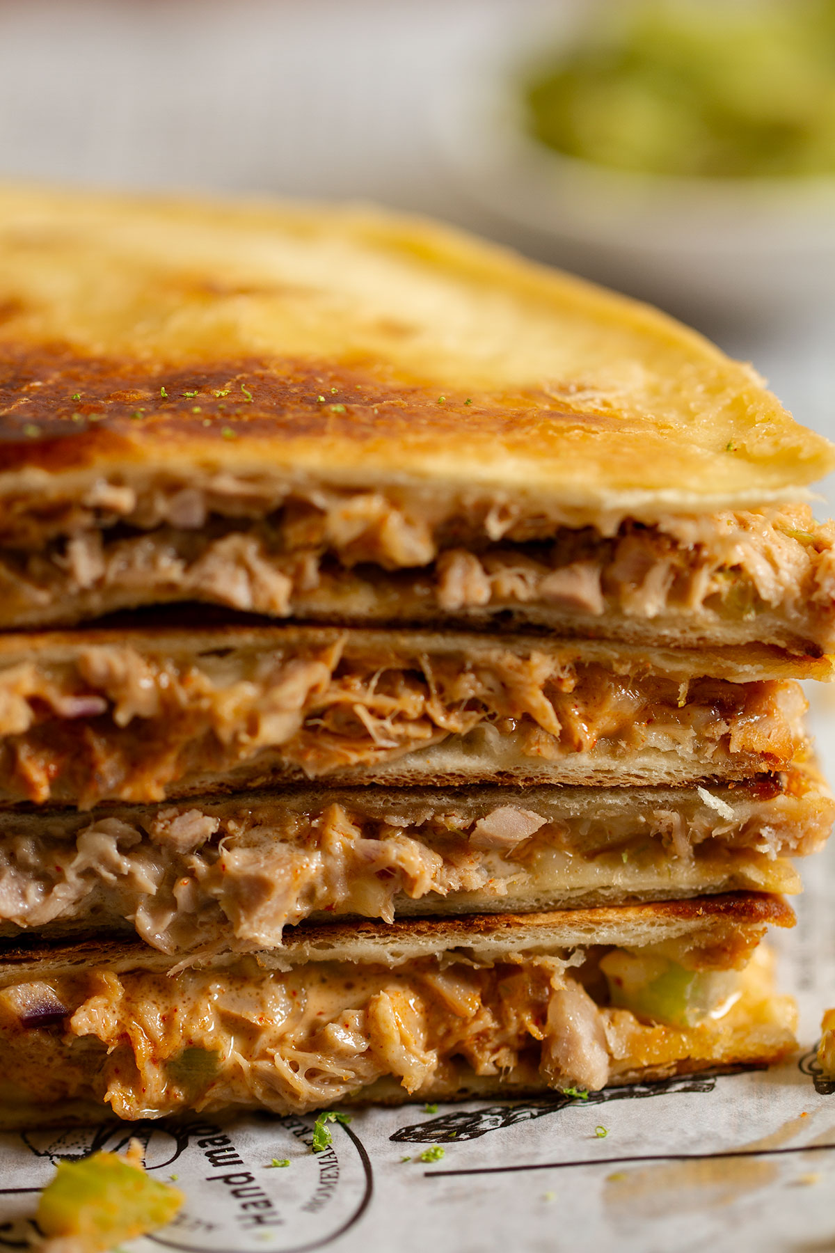 A stack of tuna melt quesadilla wraps on parchment paper.