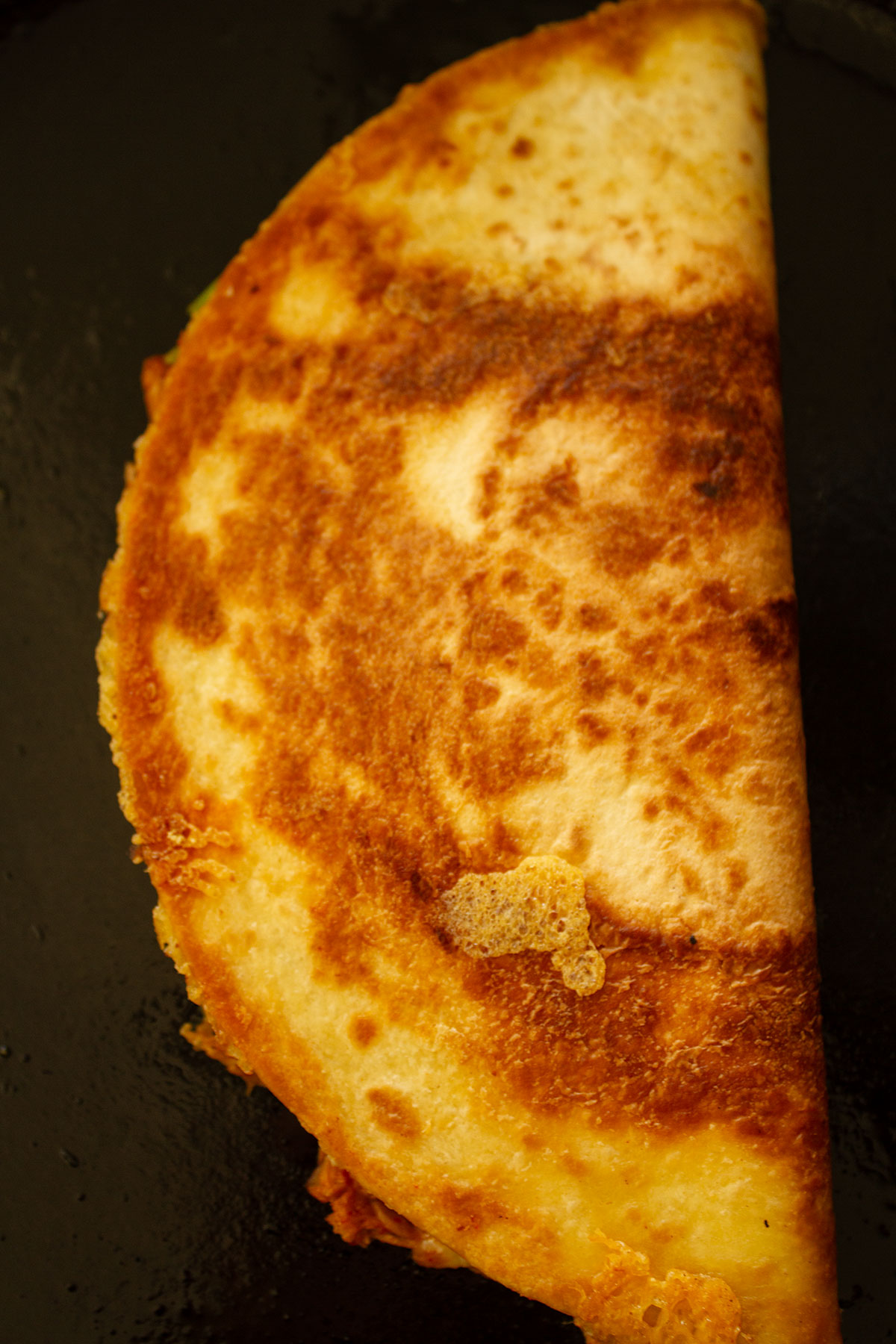 A lightly browned wrap being toasted in a skillet.