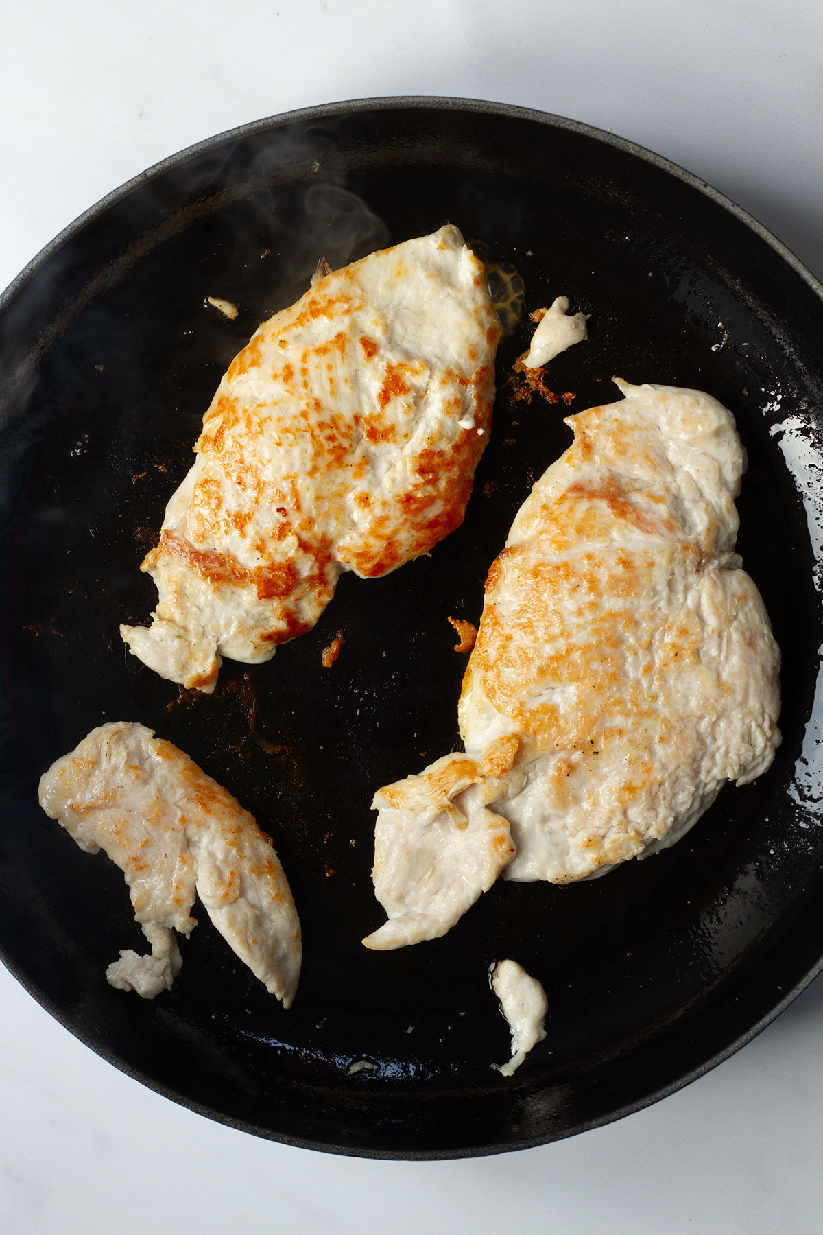 Grilling the chicken breasts for about 2-3minutes per side in a dark coloured frying pan until they are cooked through and starting to brown.