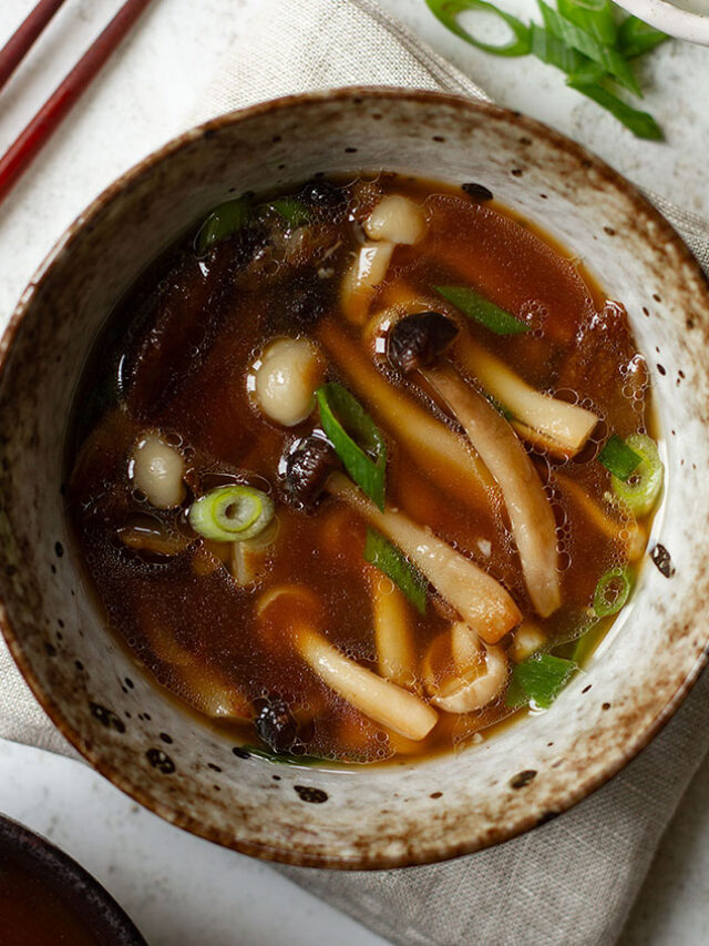 A bowl of mushroom miso soup with chopsticks on a white background.