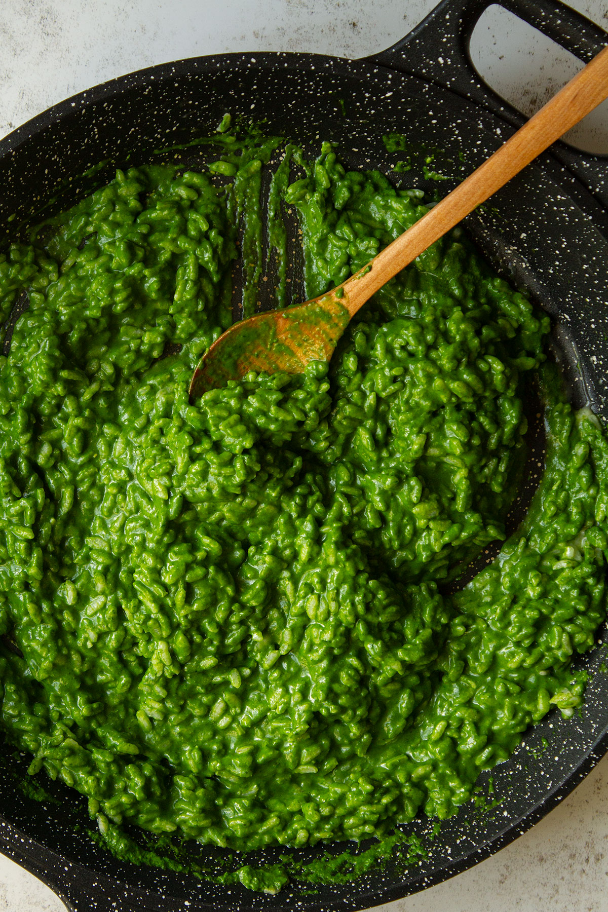 Stir the blended spinach mixture into the rice with a wooden spoon in a dark coloured skillet.