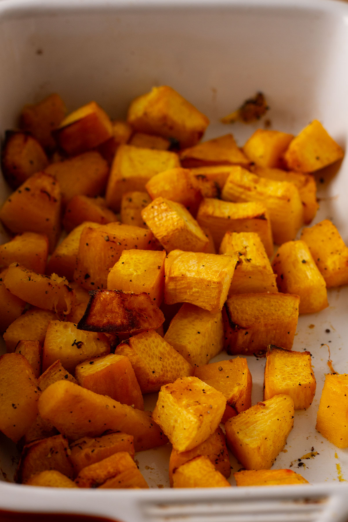 The roasted 1 inch cubes of pumpkin in a white bowl.