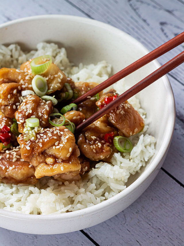 Sesame chicken on rice in a white bowl.
