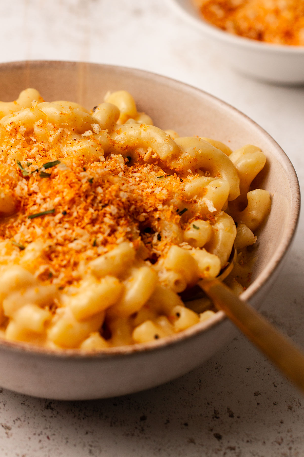 Close up photograph of Mac and cheese served in a bowl on a white background.