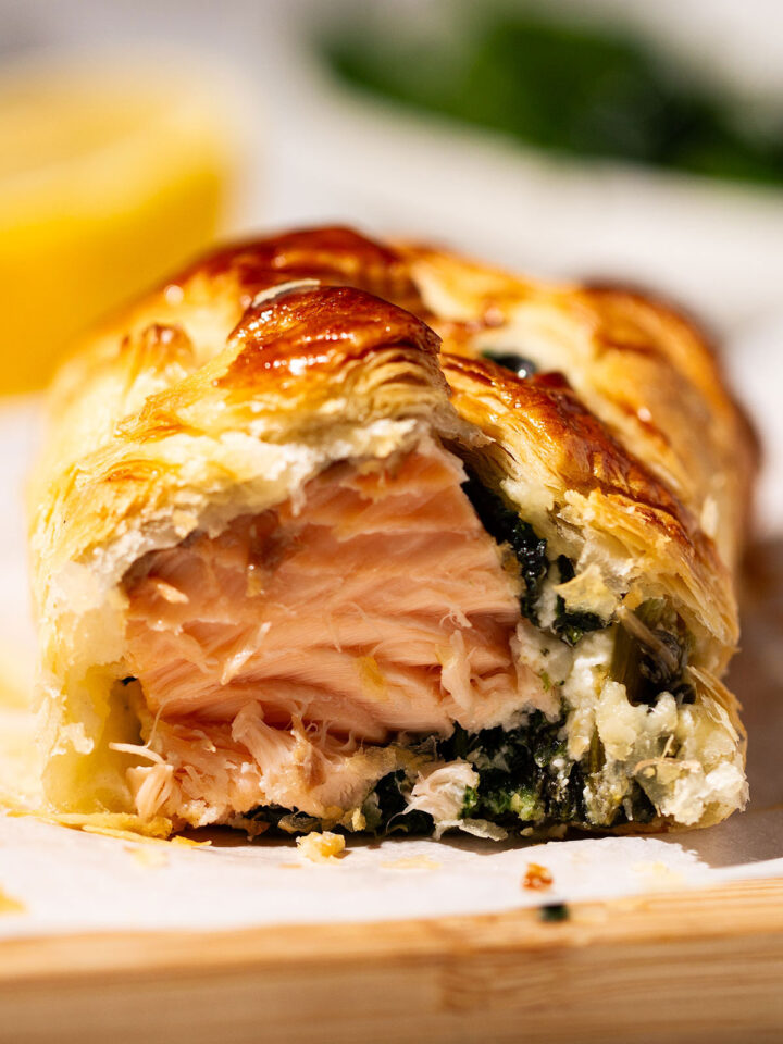 Close up of a serving of a portion of Salmon Wellington on a wooden board.