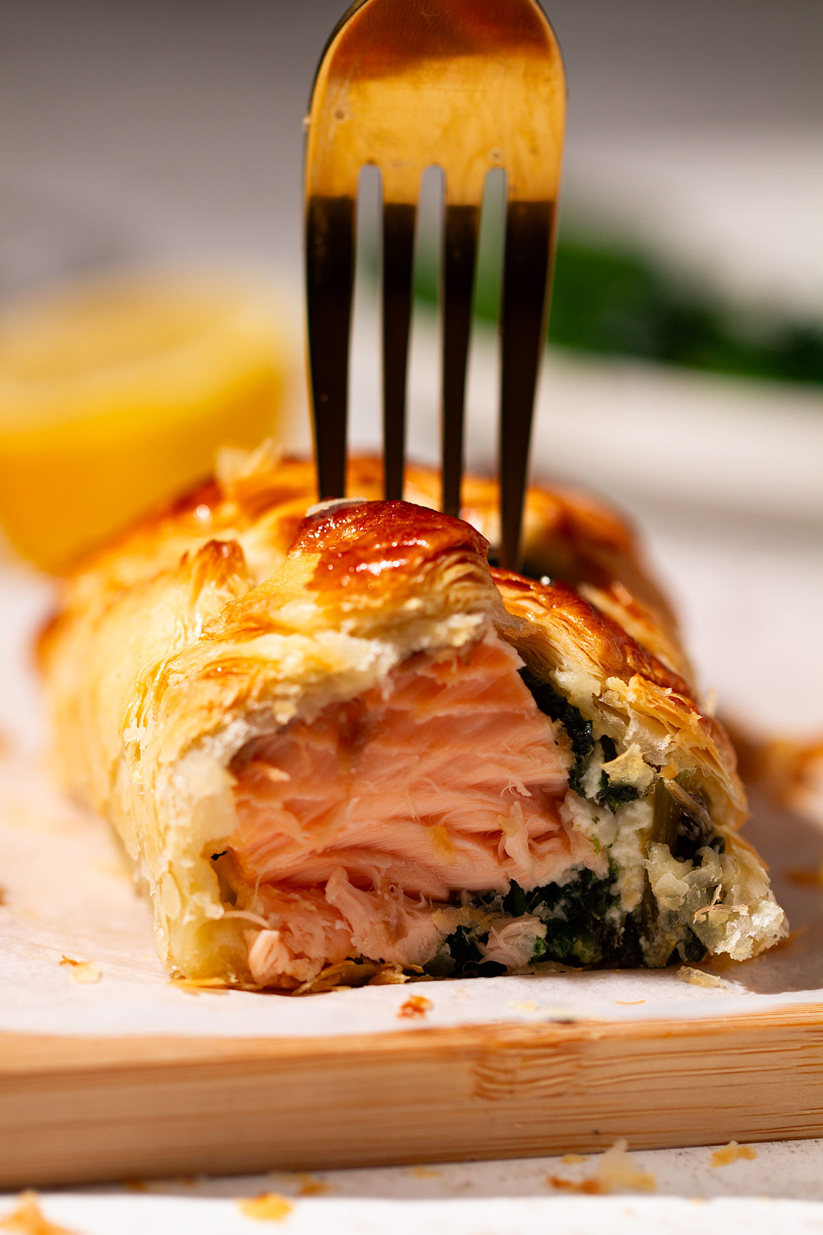 A serving of a portion of Salmon Wellington on a wooden board.