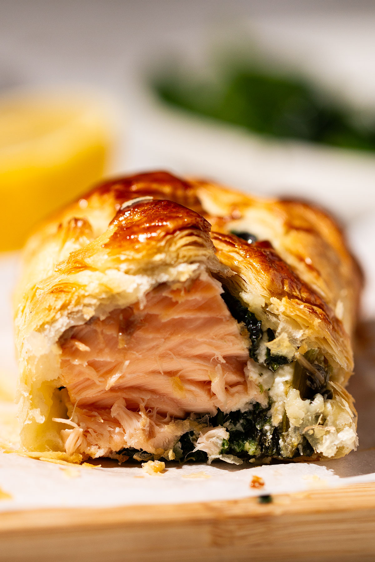 Close up of a serving of a portion of Salmon Wellington on a wooden board.