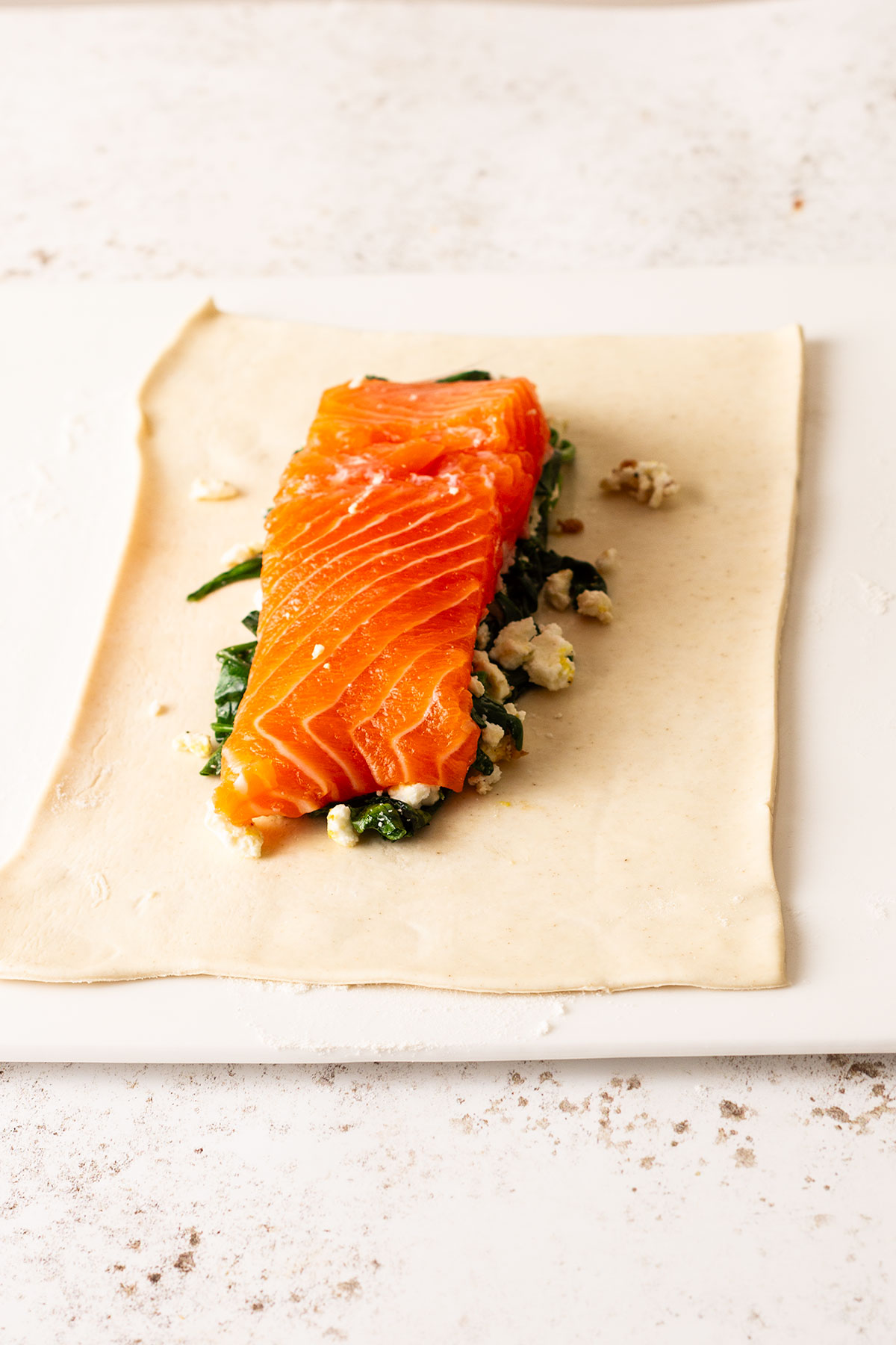 The salmon fillet in the centre of a rolled out pastry portion with the spinach and feta stuffing undrneath.