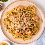 A serving of Garlic Lemon Shrimp Pasta with parsley and lemon wedges on the side.