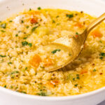 A serving of Pastina Soup with Egg in a white bowl on a white background.