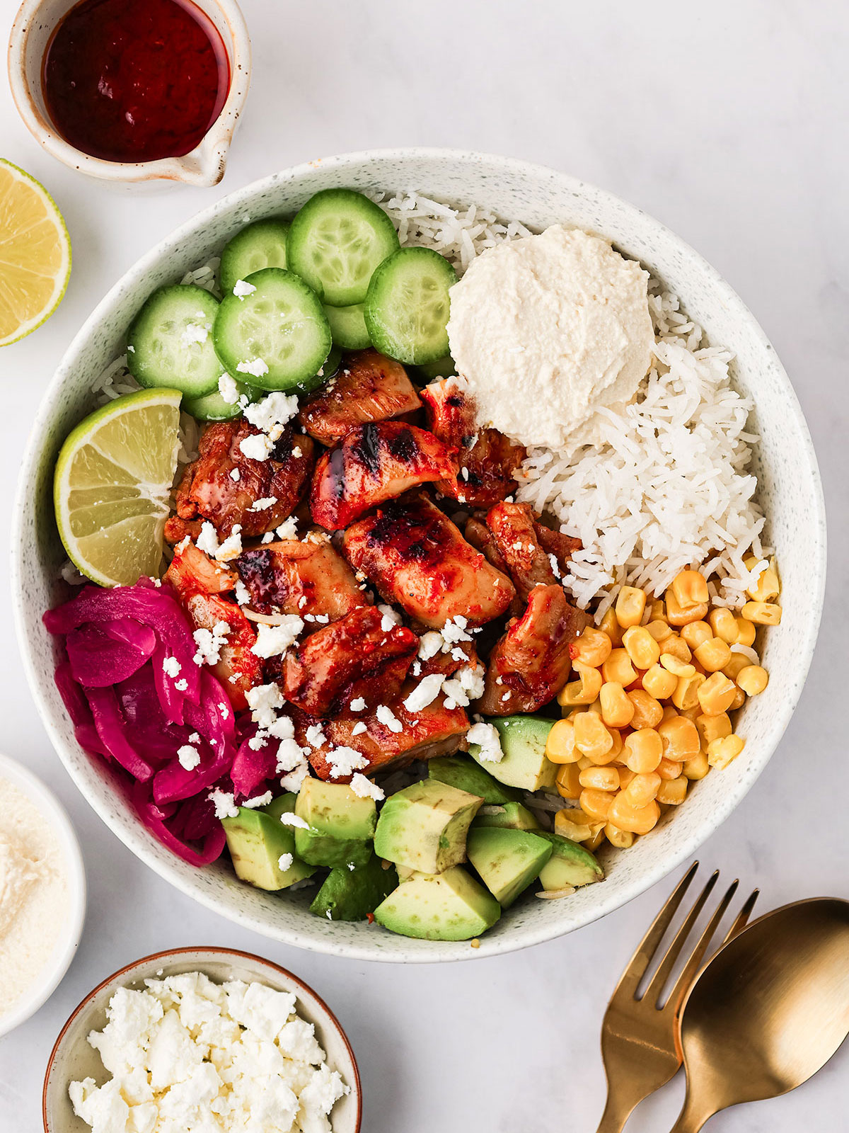 Harissa Honey Chicken cut into bite-sized pieces and served in a white Cava Bowl on a white background.