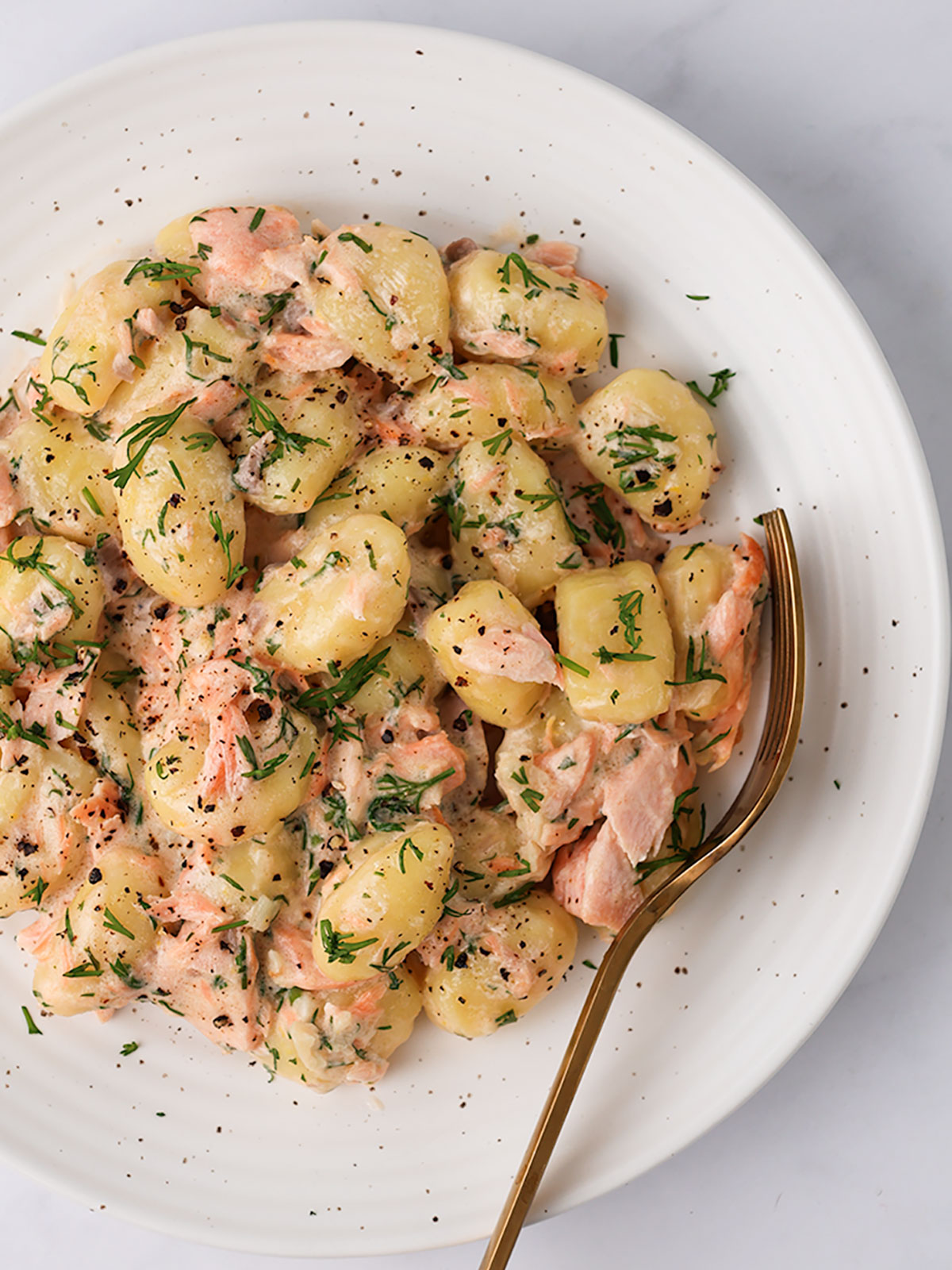 A serving of Creamy Salmon Gnocchi on a white plate.