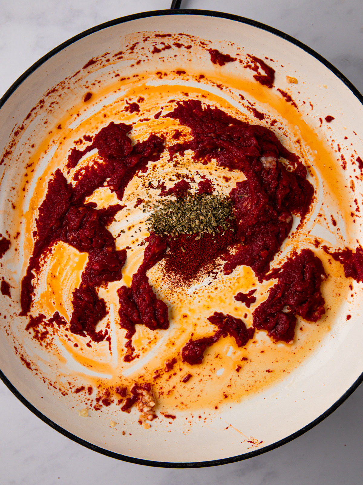 Melted butter in a large skillet with crushed garlic, tomato puree, paprika, oregano, and chilli flakes.