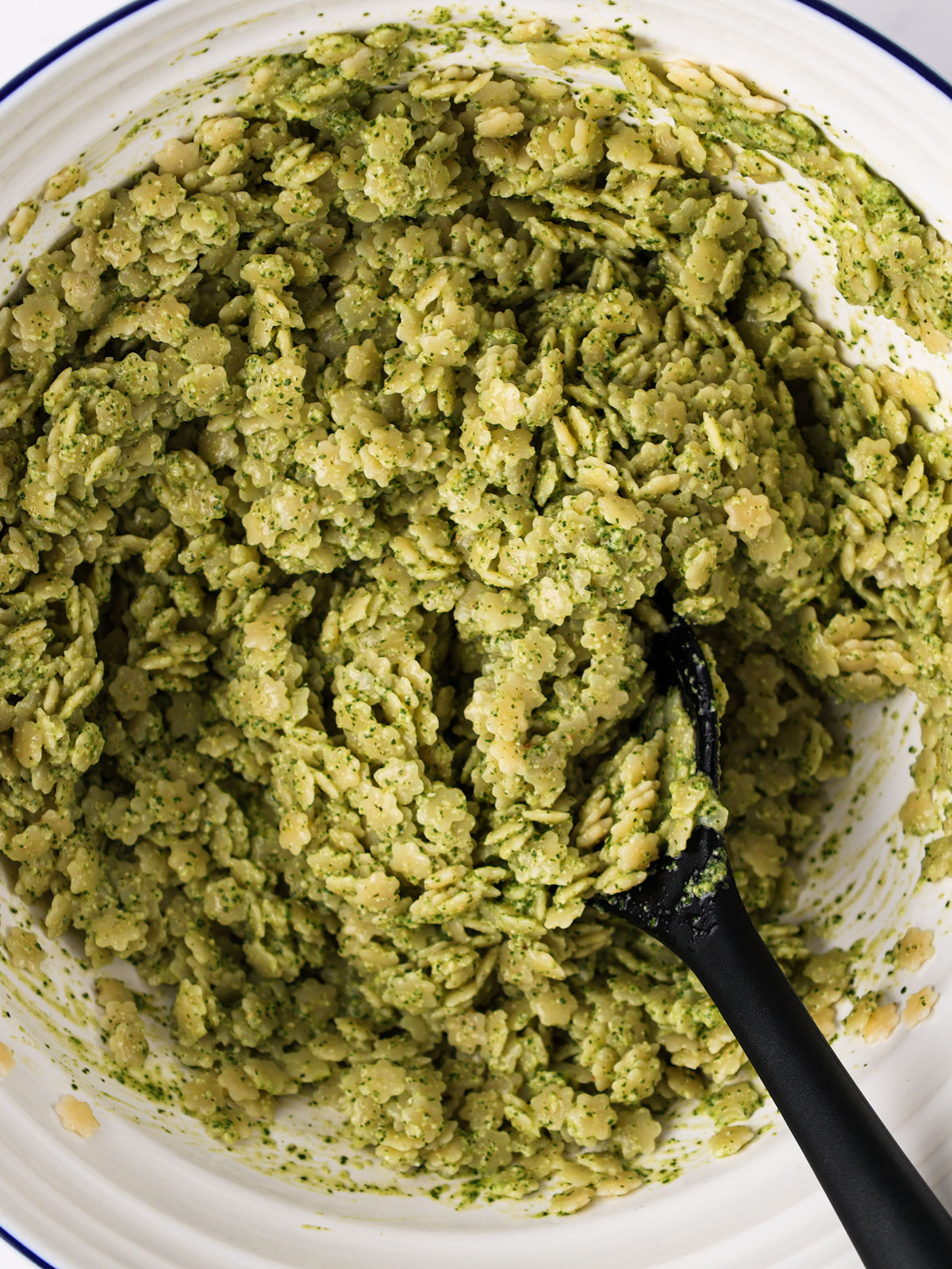 Tossing the pastina in the dressing. In a white blue rimmed bowl,