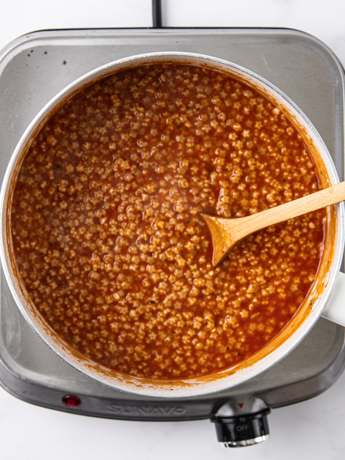 Add the pastina, reduce to medium heat, and cook, stirring occasionally, until tender. Season with salt and pepper, top with Parmesan, and serve. In a white bowl.